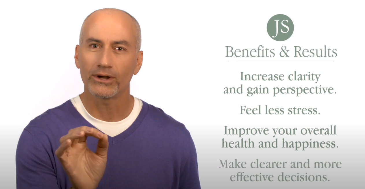 A bald man is holding his finger up to the side of his head.